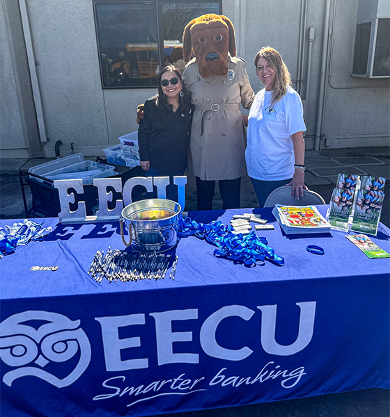 EECU staff standing behind table with McGruff mascot